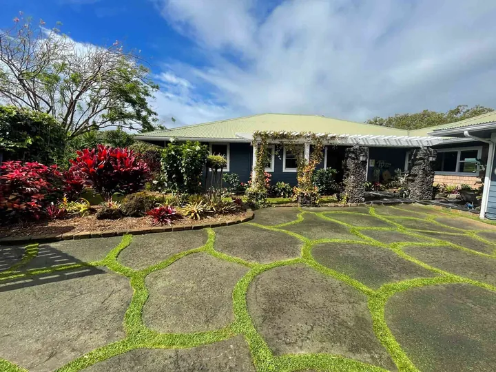 Flagstone driveway framed by red ti plants and tropical beds