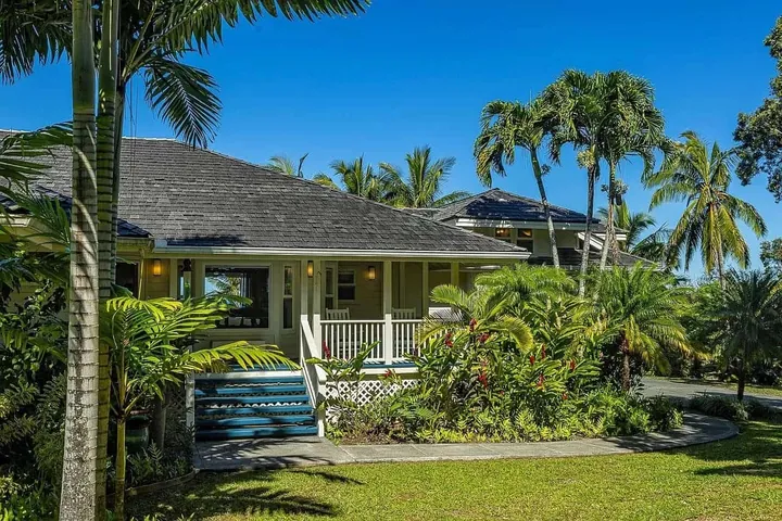 Plantation-style Maui home with palms and a green lawn